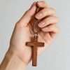 Wooden Cross Wall Decor Set small wearable wooden cross held in hand with braided lanyard necklace