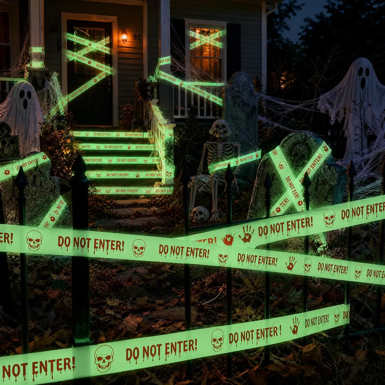 Night view of a house with glowing Halloween caution tape across the windows, front door and lawn with skeletons and ghosts