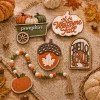 Flat lay of the five fall tiered tray decor pieces on burlap with maple leaves