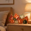 Lighted wooden pumpkin and leaf decor glowing on a bedroom nightstand next to a lamp