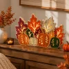 Lighted wooden pumpkin centerpiece on a wooden sideboard with dried fall florals and a candle