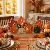 Lighted wooden pumpkin centerpiece on a Thanksgiving dining table with a plaid runner and place settings