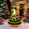 Porch goose in the Christmas tree outfit standing in snow in front of a lit house entrance with wreaths