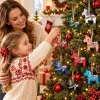 Mother and daughter hanging the colorful Dala horse ornaments on a Christmas tree beside a fireplace