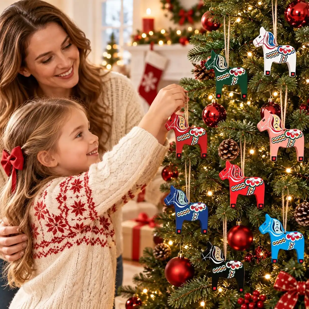 Mother and daughter hanging the colorful Dala horse ornaments on a Christmas tree beside a fireplace