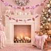 The pink gingerbread garland swagged across a white mantel with candles below, next to a flocked pink Christmas tree