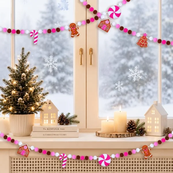 The garland draped across a snowy window with candles, books and a small lit tree on the sill