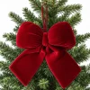Allyix large red velvet Christmas bow, 13 by 11.4 inches, hanging from a fir branch by its top loop